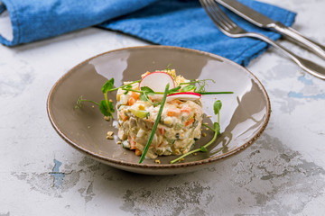 salad olivier on plate on grey table