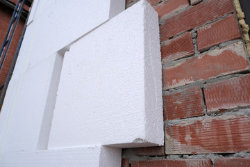 Close-up detail of brick house wall with rigid styrofoam insulation sheet. Modern technology of...