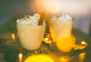 Eggnog in glasses with whipped cream and cinnamon on wooden table for Christmas and winter holidays. Copyspace included. - 292579181