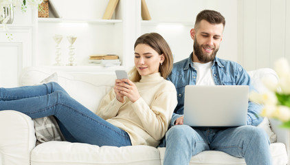 Obraz premium Para w domu. Mężczyzna z laptopem, kobieta z telefonem
