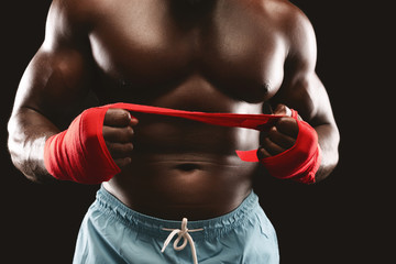 Naklejka premium Professional boxer pulling red sports bandage over black background
