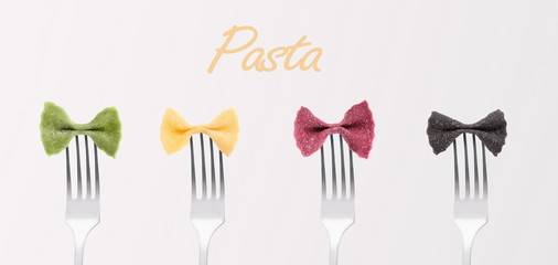 Creaive multi coloured pasta bows on forks on gray background
