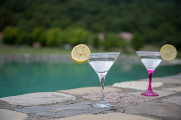 Glass of martini cocktail at swimming pool with ocean and palm tree background. A glass of blue martini cocktail welcome drink bar.Selective focus. season and holidays concept.