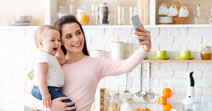 Happy mother with baby photographing themselves on cellphone