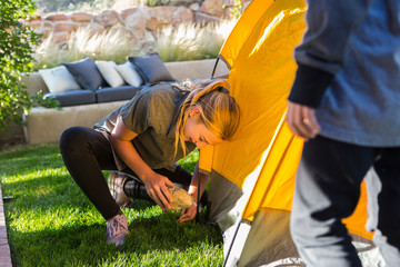 siblings setting up yellow tent on green lawn