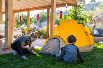 siblings setting up yellow tent on green lawn