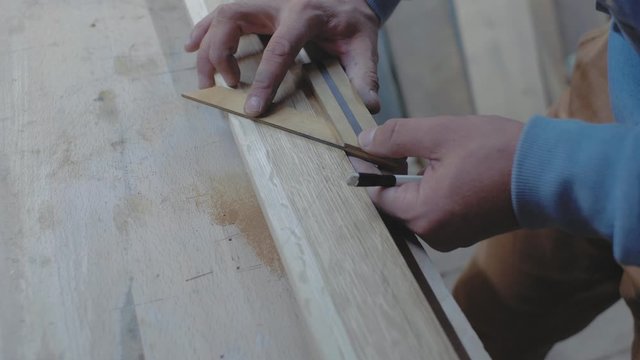 a carpenter measures a wooden board with a square at an angle and marks the dimensions with a pencil. 4k. 4k video. slow motion. 24 fps