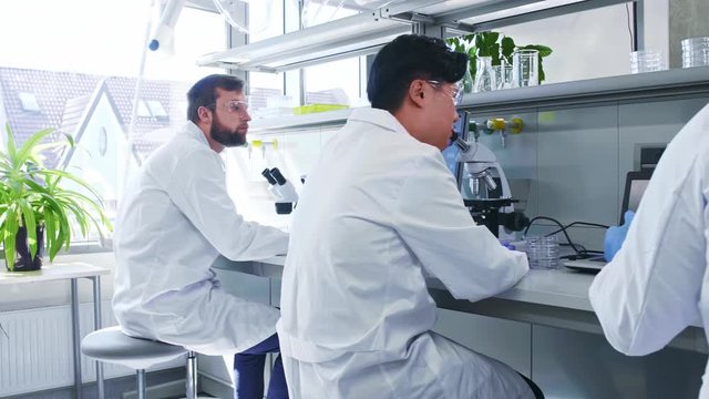 Scientist and students working in lab. Doctor teaching interns to make analyzing research. Laboratory tools: microscope, test tubes, equipment. Biotechnology, chemistry, bacteriology, virology.