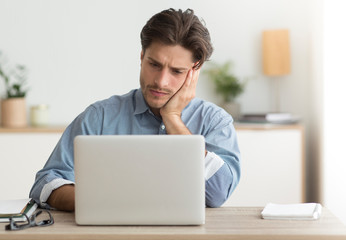Unhappy Office Manager Sitting At Laptop Working In Office