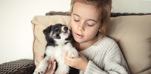 A little girl holding a puppy in her hands .
