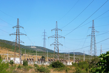 Electricity transmission pylons and blue sky. Powerful high voltage electricity poles in mountains.