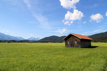 Fototapeta na wymiar Mountain huts on green meadows in the Alps