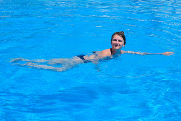 Fototapeta na wymiar Girl swimming in pool, close up on blue water