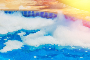 Fototapeta na wymiar Foam bubbles on the water in the outdoor pool