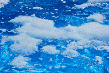 Foam on the water surface of the pool, close-up. Foam party at the hotel
