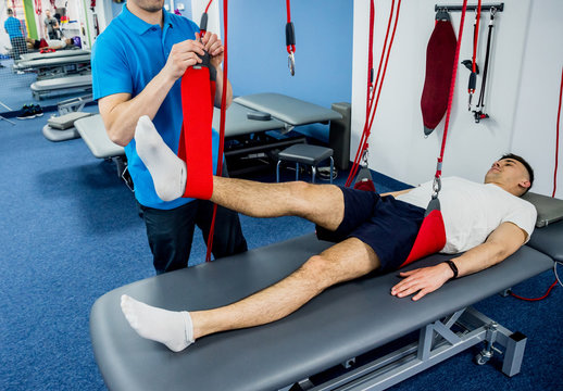 Physiotherapy. Suspension training therapy. Young man doing fitness traction therapy with suspension-based exercise training system.