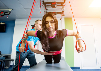 Physiotherapy. Suspension training therapy. Young woman doing fitness traction therapy with...