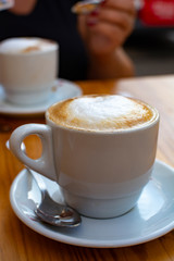 White cup with cappucino coffee with whipped hot milk