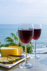 Red wine served in glasses with spanish cheese in lounge bar with sea view and palm trees