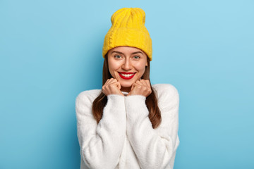 Portrait of good looking woman looks positively, smiles with pleasure, wears red lipstick, has dark...