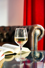 English retro style room with leather chair, open book and glas of white wine