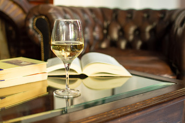 English retro style room with leather chair, open book and glas of white wine