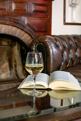 English retro style room with leather chair, open book and glas of white wine
