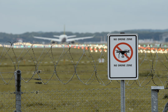 Sign at the Airport "No Drone Zone" with airplane in the background