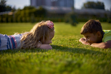 portrait of two happy smiling kids lying on green grass. Cheerful brother and sister laughing together.Happy children have funny time at park lawn. Kids day