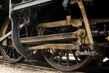 Industrial or transportation or steam punk vintage background with detail of old rusty steam locomotive featuring crank mechanism, frame and  wheels. 