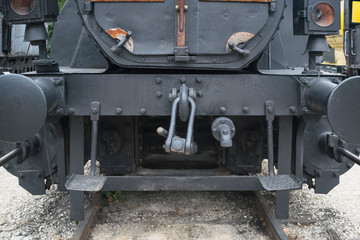 Fototapeta na wymiar Industrial or vintage technology background featuring detail of old steam locomotive front view with head lights, metal rivets and hook railway coupling