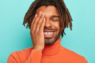 Close up portrait of happy pleased African American man smiles broadly, has white teeth with little...