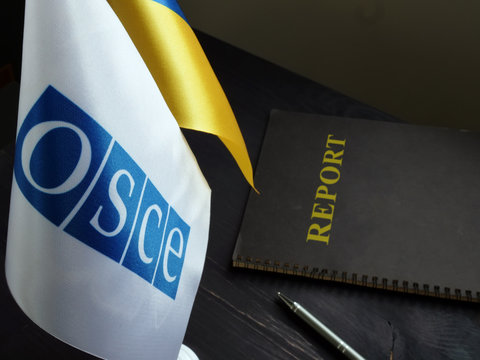 OSCE and Ukrainian flags with report on the desk.