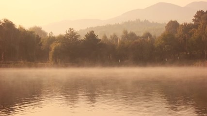 Foggy morning on a lake during sunrise. Summer landscape on a mountain lake. Peaceful summer scene.