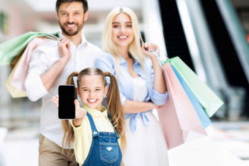 Happy Family Showing Phone Screen Standing In Shopping Mall, Mockup