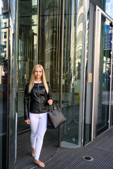 Close up portrait of a trendy young woman coming out from a business building in the business district of London, England