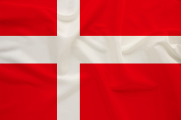 Obraz premium The national flag of the country of Denmark on the gentle silk with folds from the wind, the concept of travel, immigration, politics, copy space, close-up