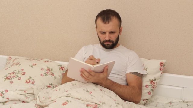 a man writes a diary before going to bed