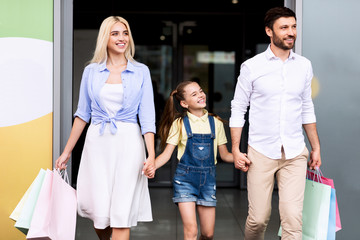 Family Of Three Leaving Shopping Mall Carrying Bags