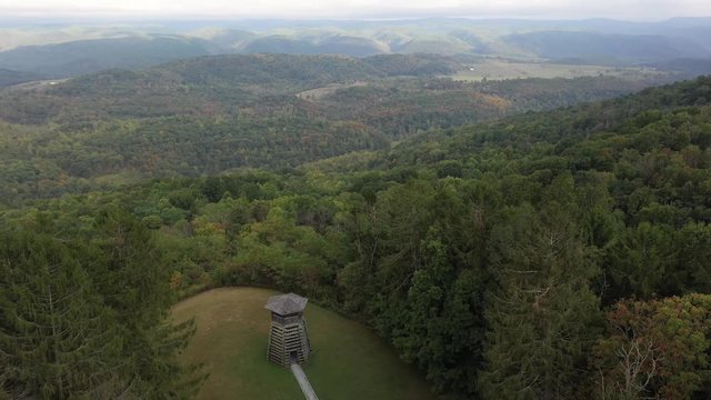 Aerial camera ascending and flying backwards to reveal the overlook tower at Droop Mountain State Park in West Virginia and the mountains and valley around.