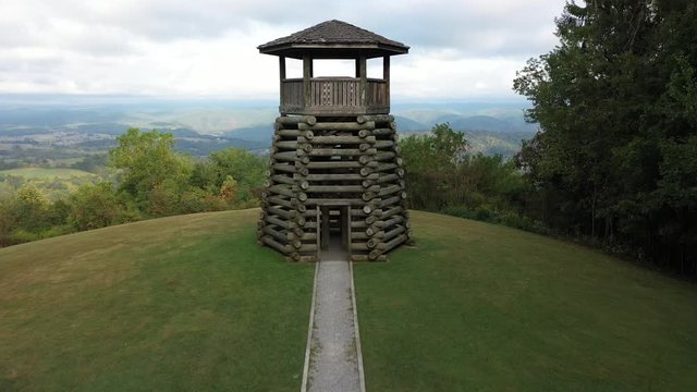 Low aerial camera flying towards and ascending to fly over the overlook tower at Droop Mountain State Park.