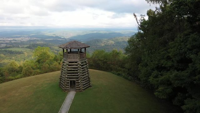 Aerial camera flying backwards to reveal Droop Mountain State Park&rsquo;s overlook tower and its setting high on a mountain.