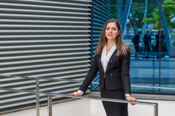 Confident businesswoman in front of modern office building. Business, banking, corporation and financial market concept.