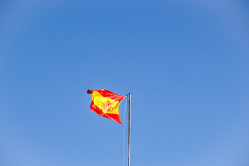 Spanish flag on a pole,waving in the wind against clear blue sky background
