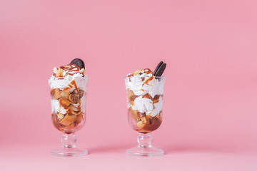Sweet dessert in glass with biscuit and whipped cream on pink bsckground, selective focus and blank space