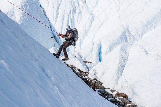 Rappelling Down An Icy Slope On A Glacier In Alaska.