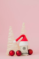 Christmas expenses. Pink leather purse with santa claus cap, gift, fir tree and dollars banknotes on pink background. Christmas shopping. Holiday Sale