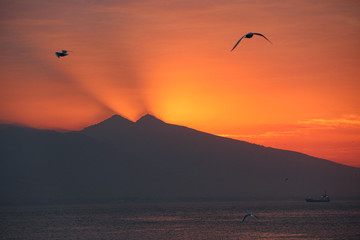 Stunning sunset behind the mountain with seagulls flying over the sky in Turkey
