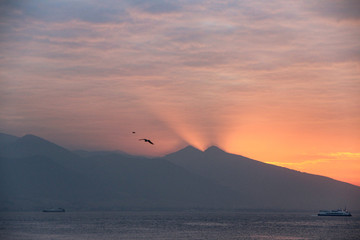 Naklejka na ściany i meble Stunning sunset behind the mountain with seagulls flying over the sky in Turkey