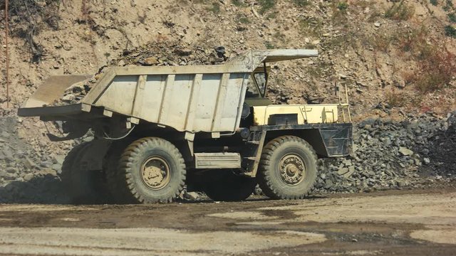 Mining dump truck riding on the road at quarry. Mining truck carrying stone. Heavy truck in open cast mine.